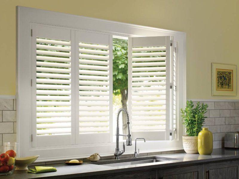 Partially open Hunter Douglas Palm Beach™ Polysatin™ Shutters on a kitchen window above the sink