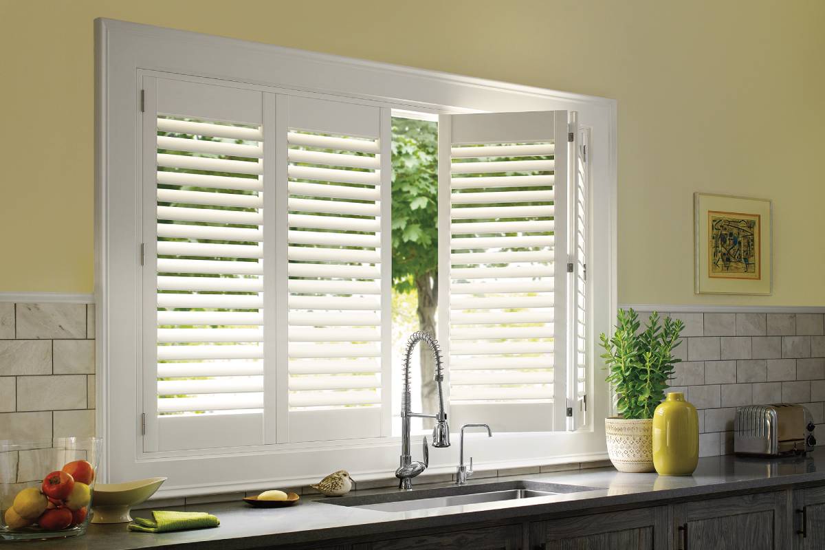 Partially open Hunter Douglas Palm Beach™ Polysatin™ Shutters on a kitchen window above the sink